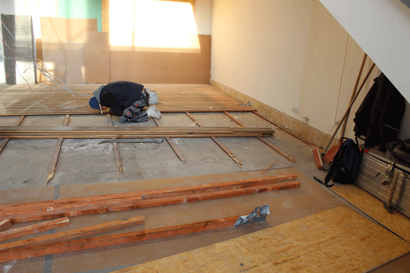 Gerade fliegt der Holzfußboden raus: „Unter der Treppe haben wir entedeckt, dass sich unter dem Holzfußboden kein hässlicher PVC-Belag verbirgt, sondern wunderschöner alter Kalkstein“, erklärt CAMP4 Chef Andreas Hille. Dieser Kalkstein wird jetzt restauriert.